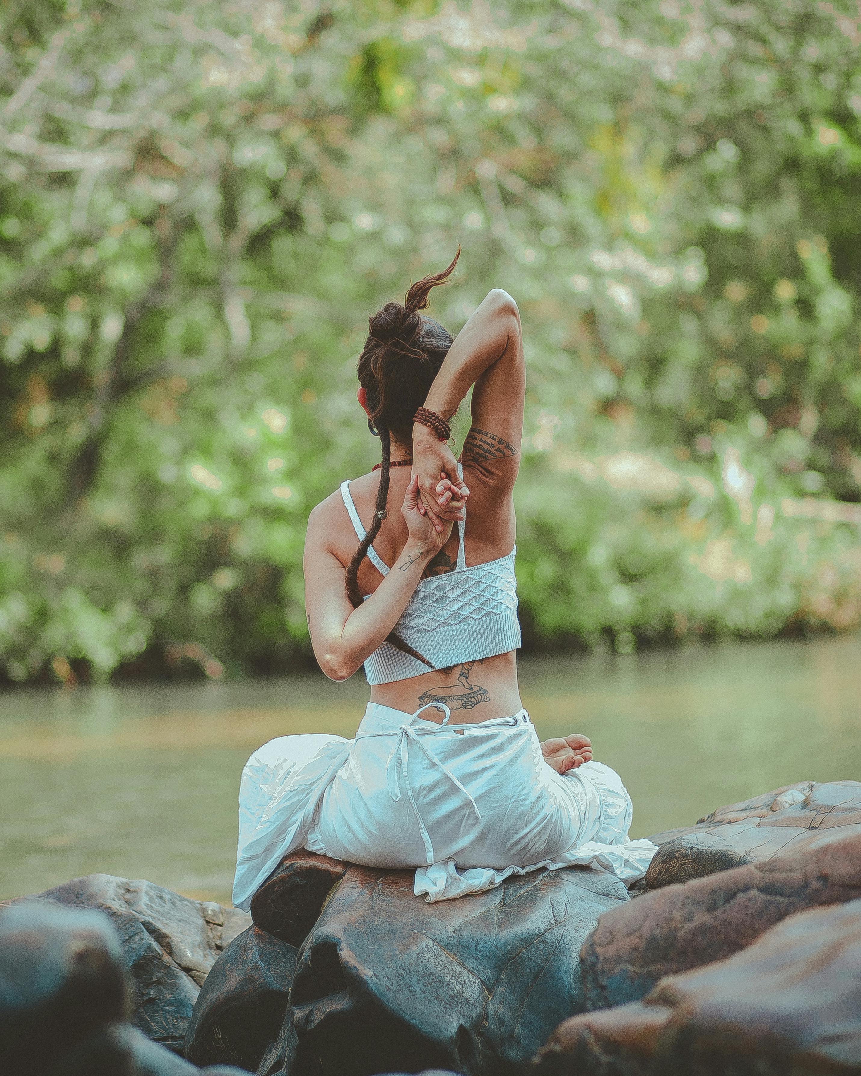 Woman in meditation pose by the water